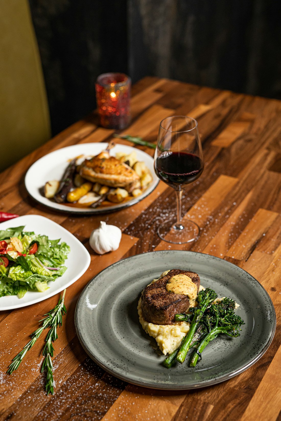 Steak dinner with sides and a glass of wine at a restaurant table