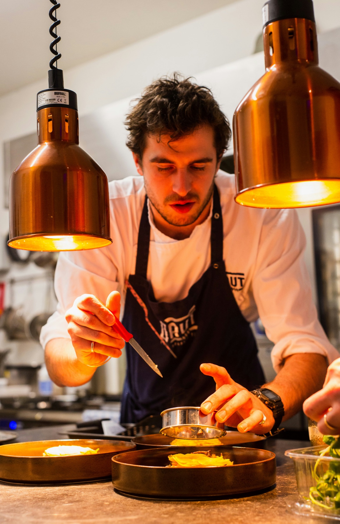 Chef carefully plating a dish under warm kitchen lights